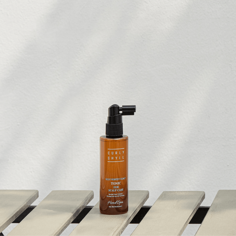 Bottle of Curlyshyll hair tonic on a wooden surface with a white background